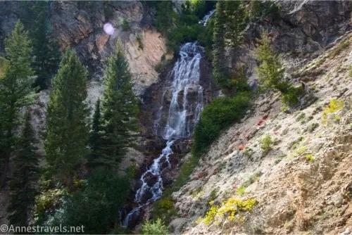 A waterfall tumbles between trees and steep hillsides