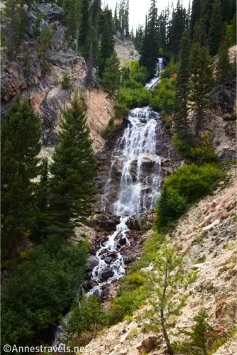 A waterfall cascades between trees and steep hillsides