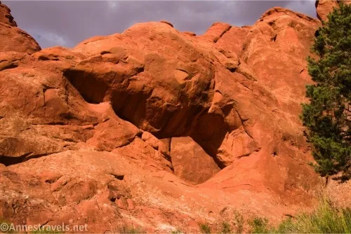 A hole in a slickrock fin with another red slickrock fin behind the hole 