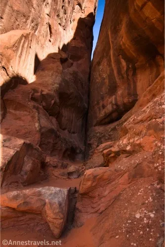 Red cliff canyon walls with a sliver of blue sky