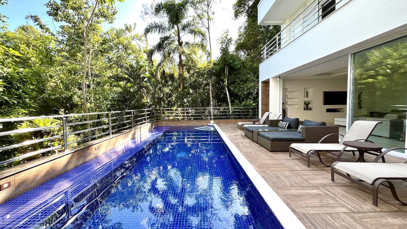 Piscina com deck de madeira e vegetação ao redor