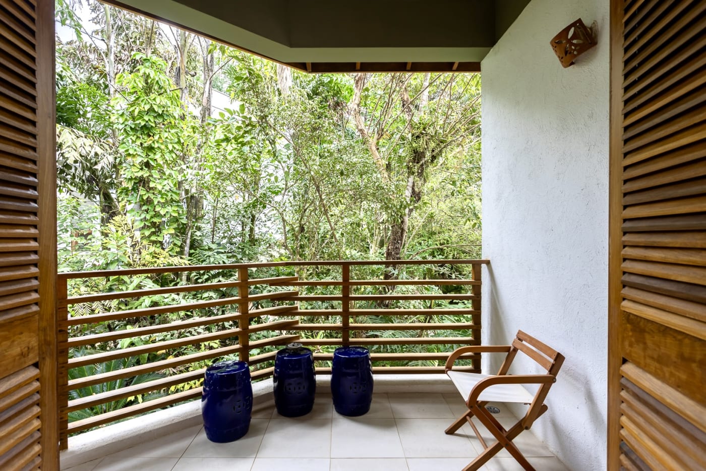 Varanda com guarda-corpo de madeira e vista para o verde