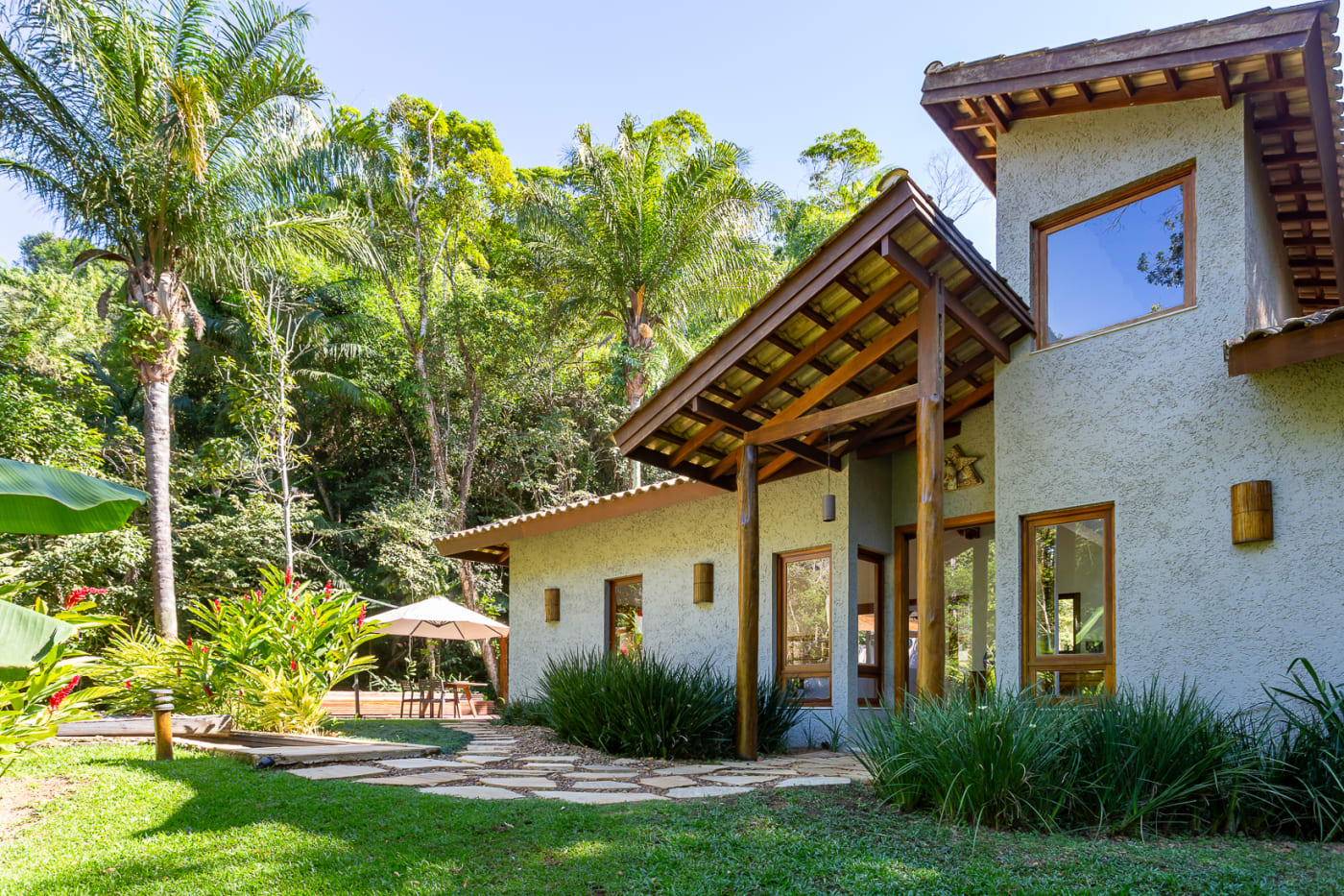 Fachada com estrutura de madeira e paisagismo exuberante
