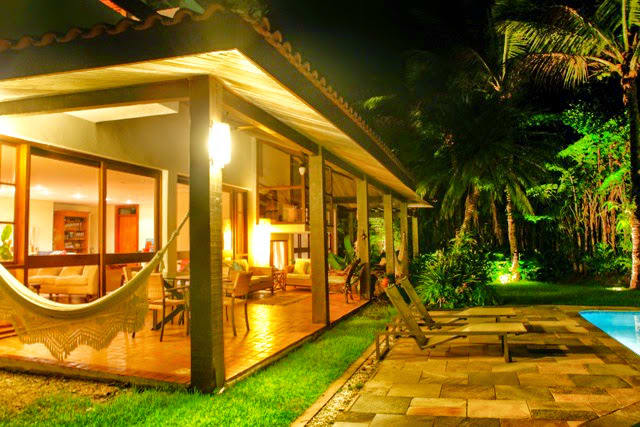 Varanda integrada ao jardim com iluminação noturna
