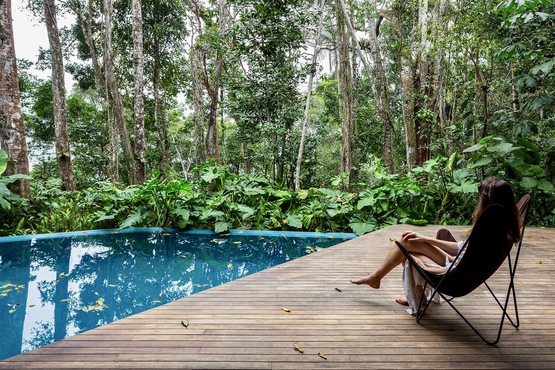 Piscina com deck de madeira em meio à natureza
