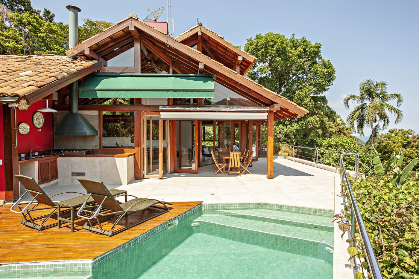 Piscina com deck de madeira e área gourmet integrada
