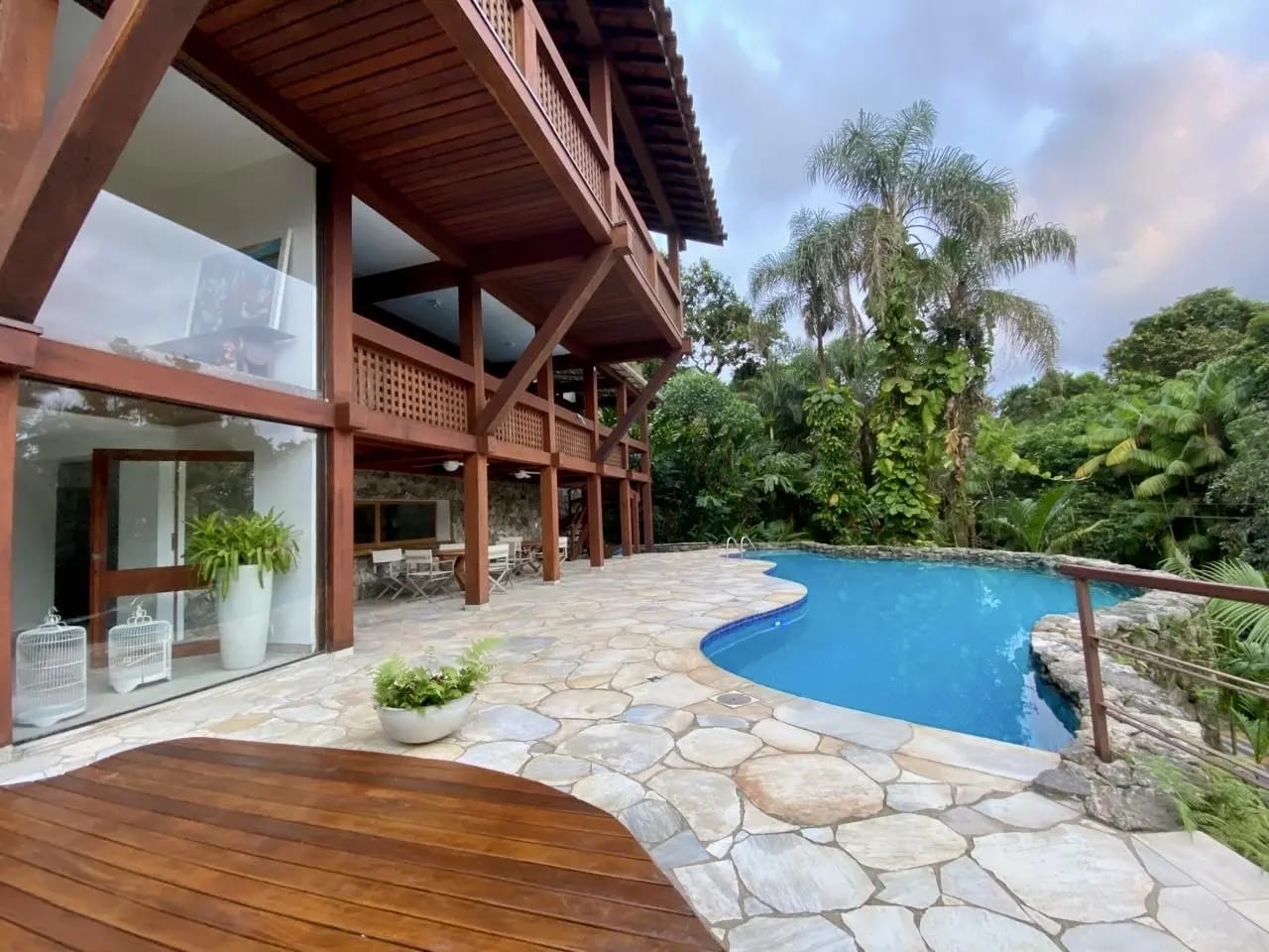 Piscina integrada com deck em pedra e madeira