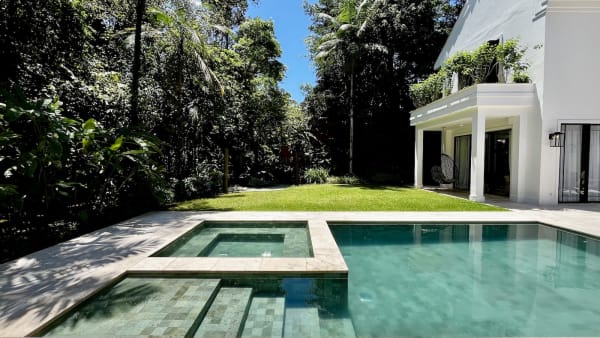 Piscina com spa em destaque e fachada ao fundo