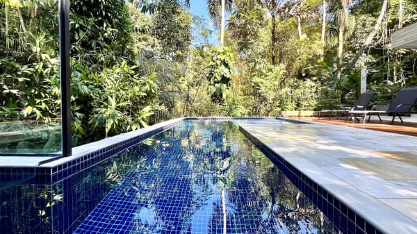 Piscina de pastilhas cercada por vegetação tropical