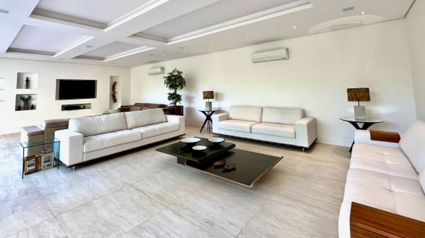 Sala ampla com sofás claros e piso em porcelanato