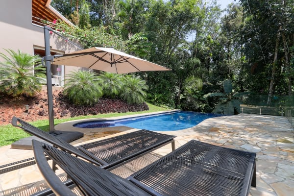 Piscina com deck em pedra natural e jardim