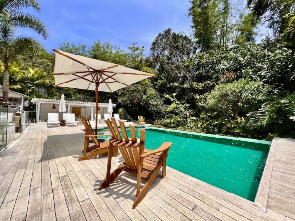 Piscina integrada ao jardim com deck e espreguiçadeiras