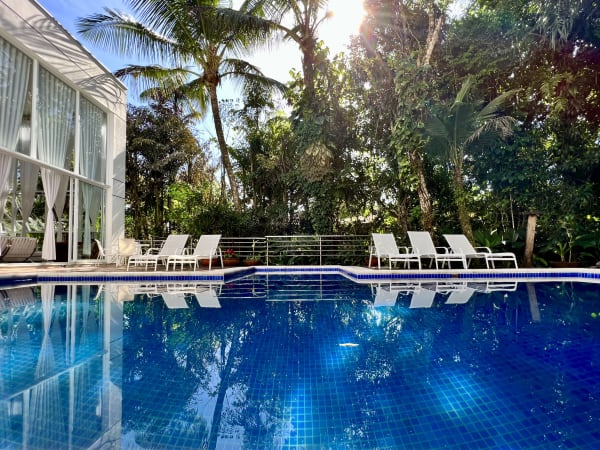 Piscina com deck em madeira e jardim tropical