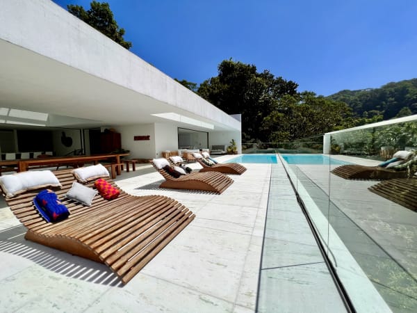Piscina com deck em mármore e espreguiçadeiras em madeira