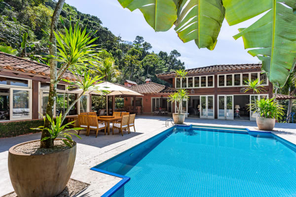 Fachada com piscina e vegetação exuberante ao fundo