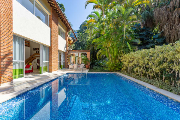 Piscina cercada por vegetação nativa e deck
