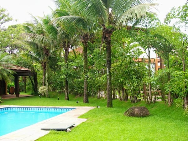 Piscina com jardim tropical e área sombreada