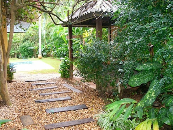 Caminho em pedra e seixos pelo jardim tropical