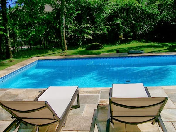 Espreguiçadeiras à beira da piscina com jardim