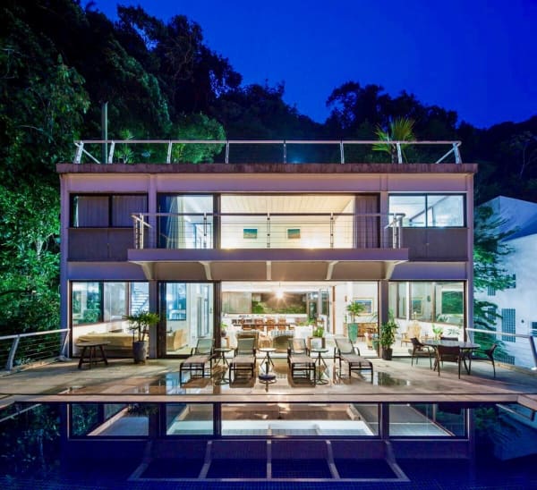 Fachada posterior com piscina e integração noturna