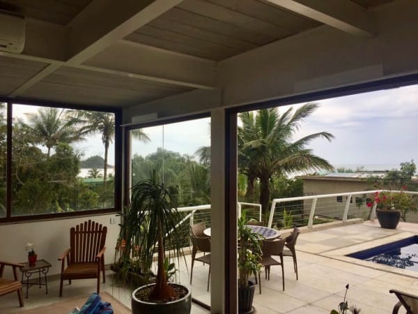Varanda integrada com piscina e jardim tropical