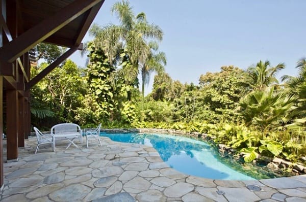 Área externa com piscina e jardim tropical