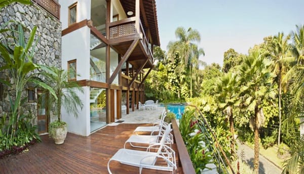 Fachada posterior com deck em madeira e jardim tropical