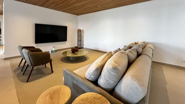Sala de TV em continuidade com o espaço gourmet, próxima ao deck e à piscina.