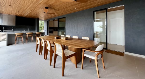 Espaço gourmet com mesa em madeira e acabamento em pedra