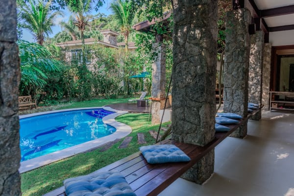 Espaço coberto com pilares de pedra e vista piscina