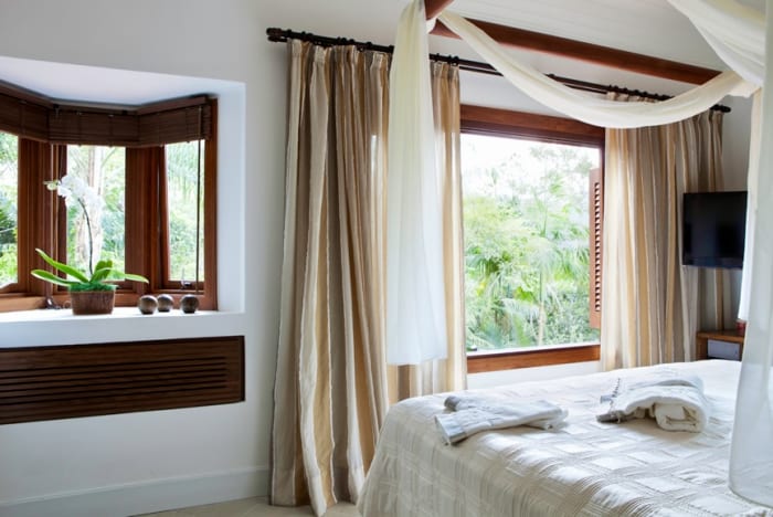 Quarto amplo com esquadrias de madeira e vista verde
