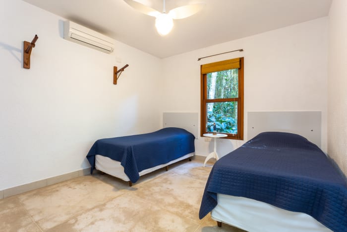Quarto com duas camas e janela voltada ao verde