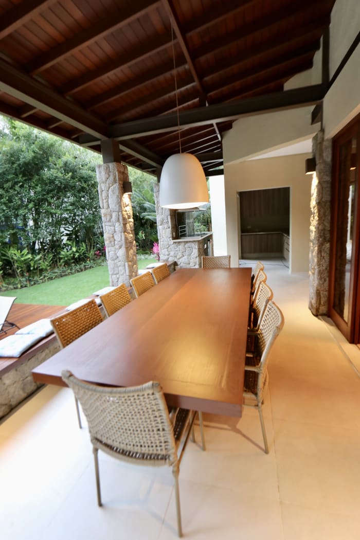 Varanda gourmet com mesa ampla e forro de madeira