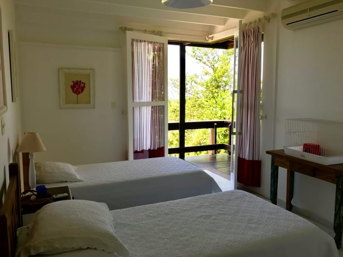Quarto com duas camas e acesso à varanda