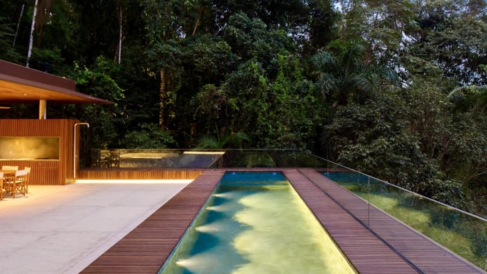 Piscina com iluminação noturna e vista para mata