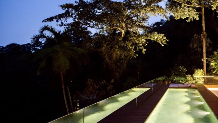 Piscina com iluminação noturna e paisagismo tropical