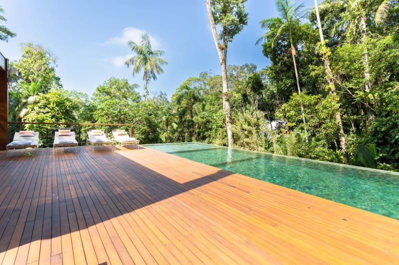 Piscina de borda infinita envolvida por vegetação tropical