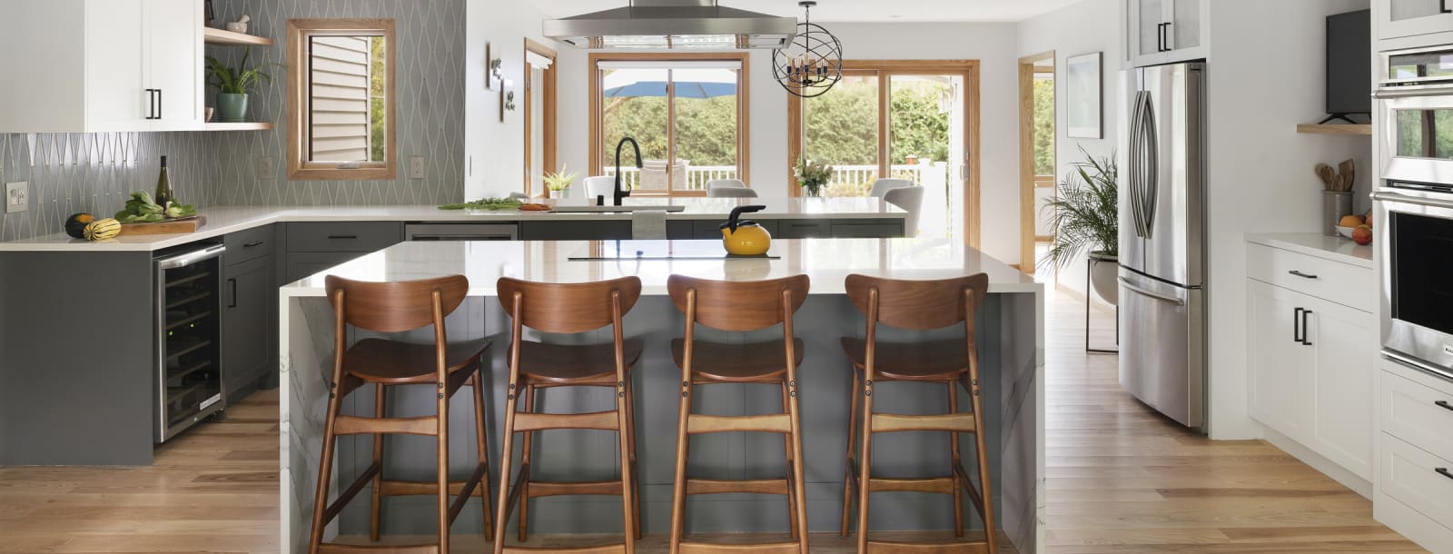 A view of the New Brighton Upgrade kitchen remodel showing the large, stone waterfall island with barstools.