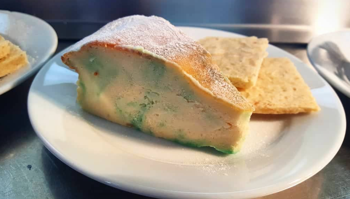 A wedge of stilton cheese that's actually made of cheesecake, on a white plate, by chefbenchurchill on instagram