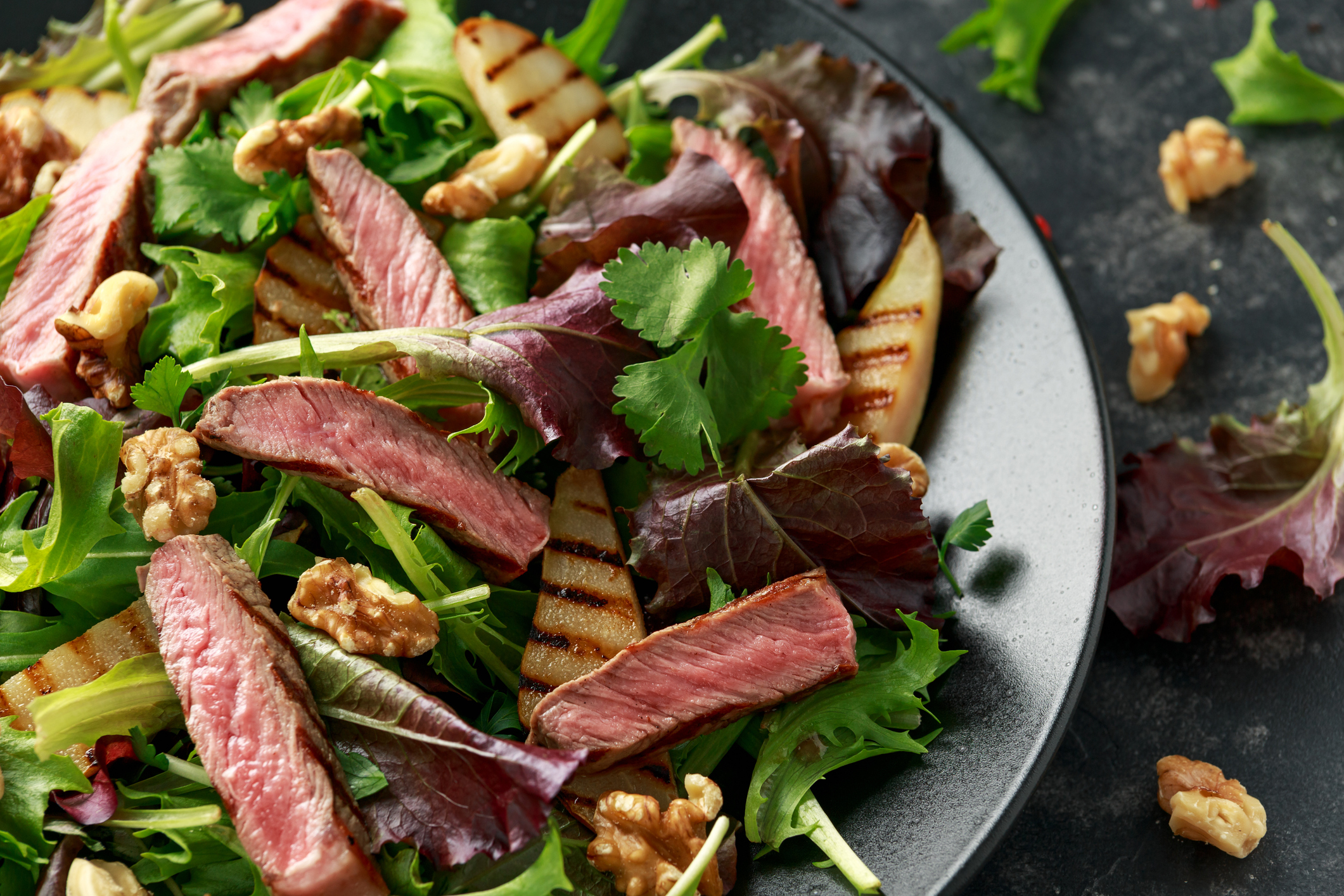 Grilled Beef Steak salad with pears, walnuts and greens vegetables and blue cheese sauce. healthy food