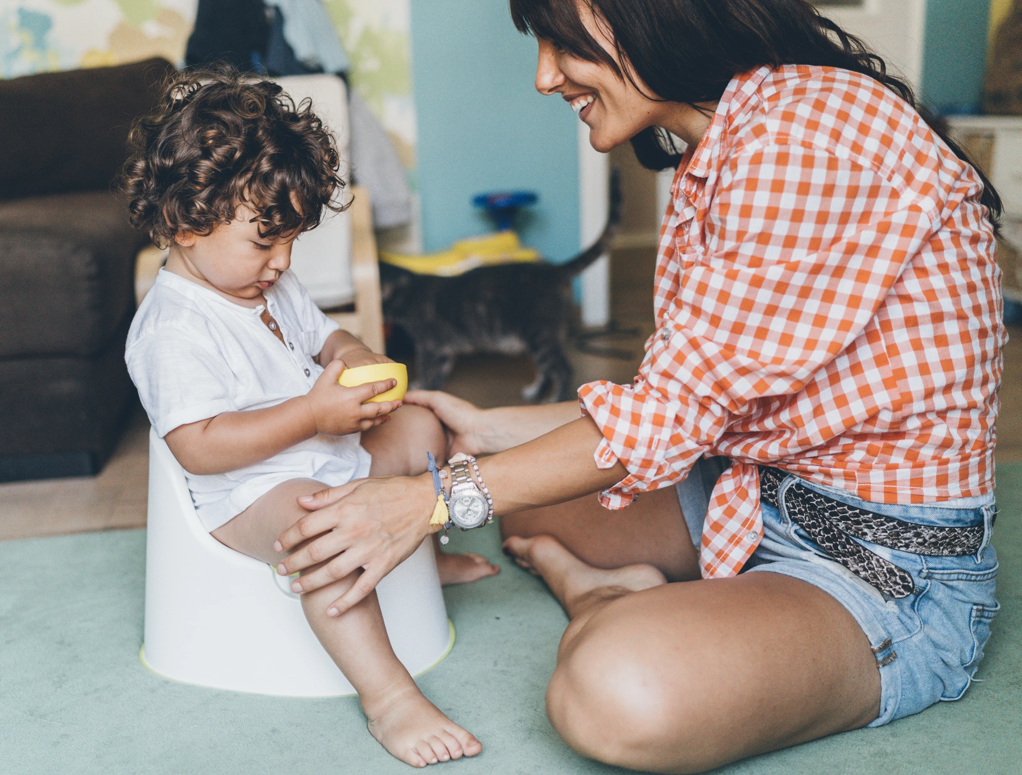 Mother teaching her baby boy how to use pot