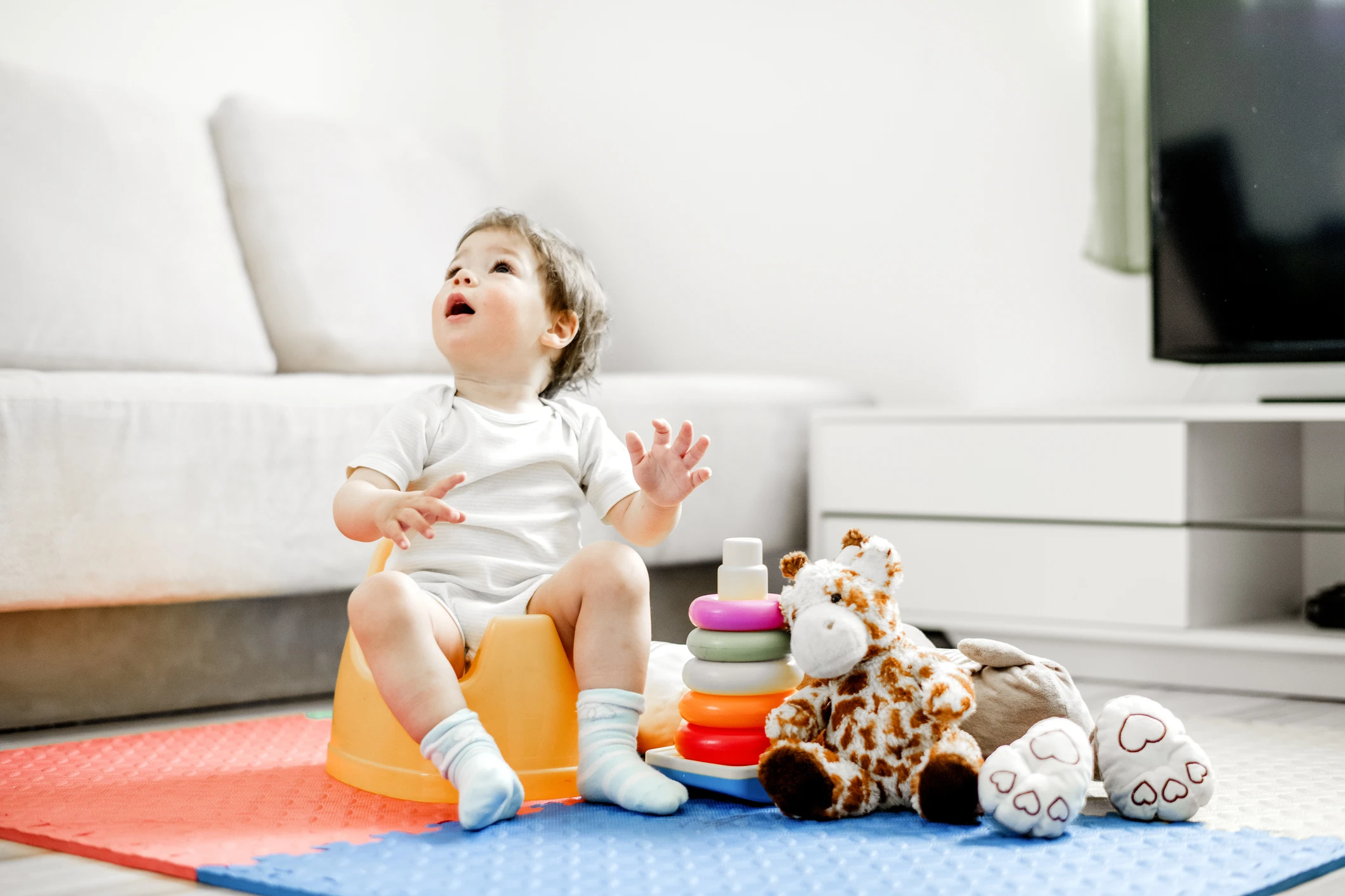 Cute Baby boy on yellow potty looking up