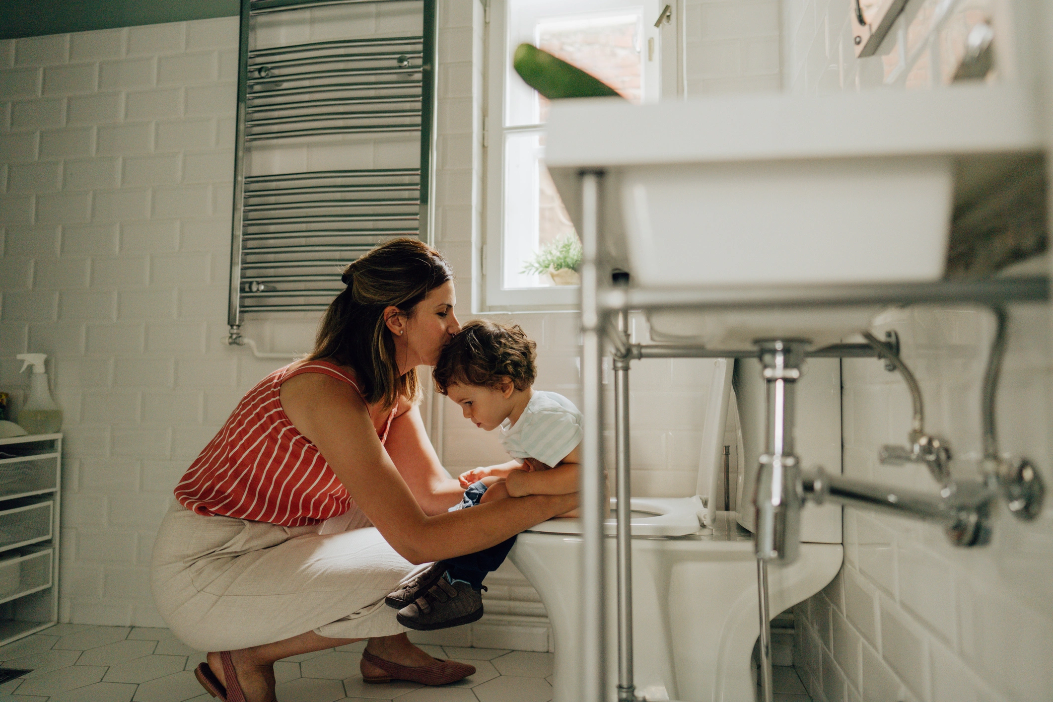 Photo of a little boy learning to use toilet amenities with a little help from his mother