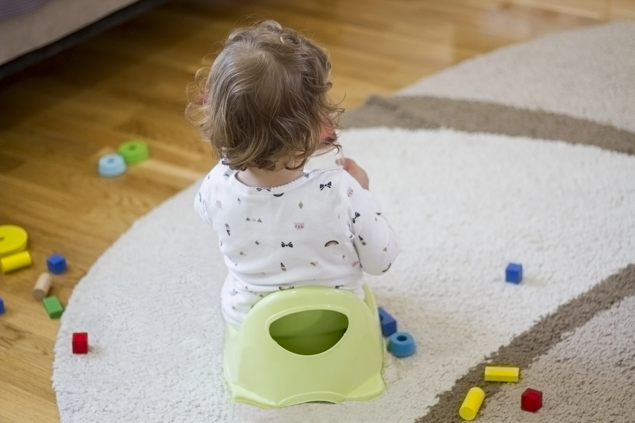 Child sitting on potty and playing with colorful toys