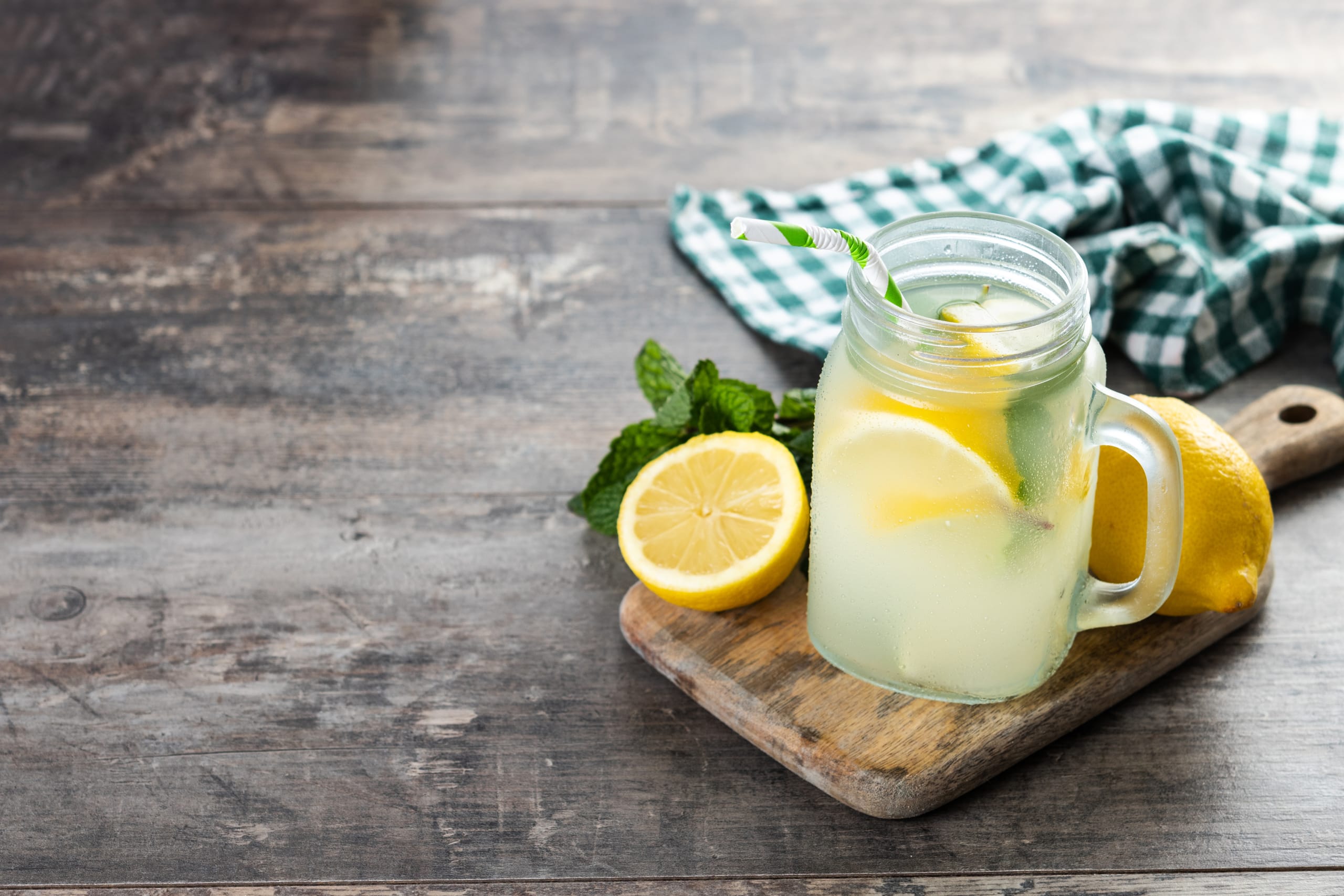 Lemonade drink in a jar glass and ingredients on wooden table