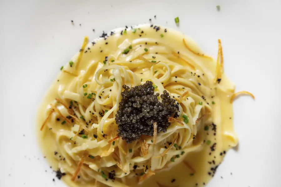 Spaghetti with sauce, sweet potatoes and black caviar in a plate