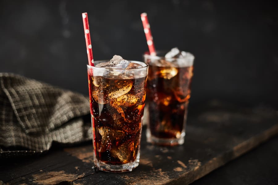 Close up glass of refreshing cola with ice on table.