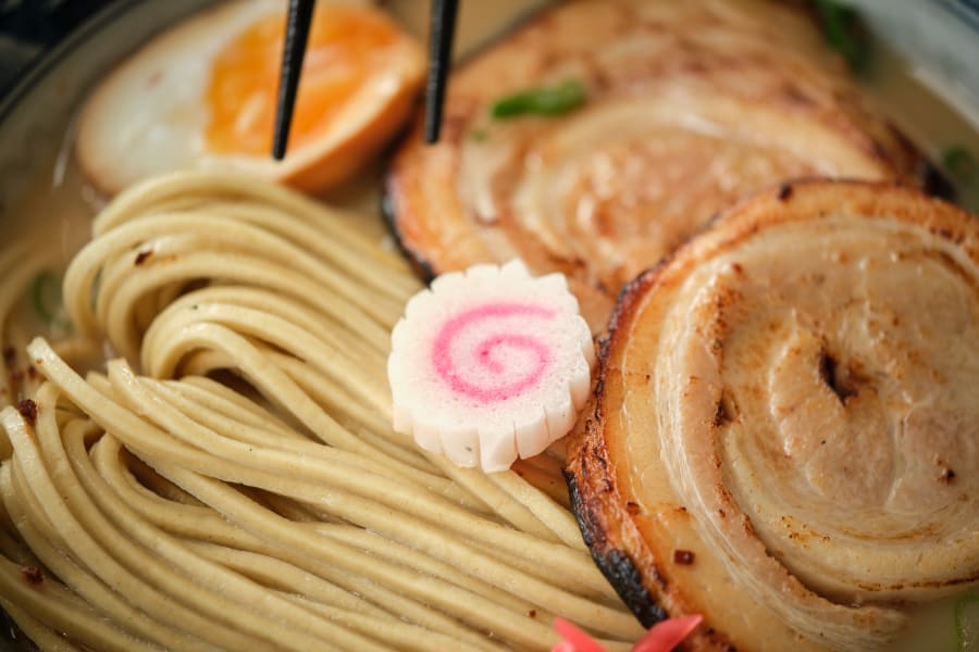 Closeup of narutomaki in tasty Japanese ramen soup with noodles meat and boiled egg in bowl