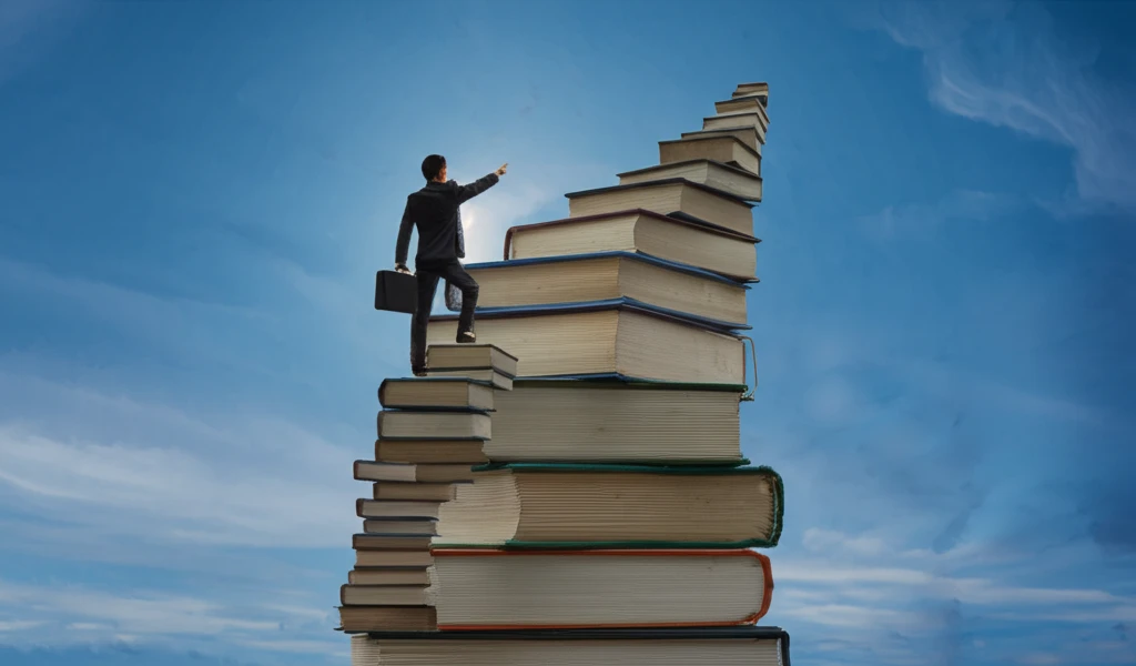 Person climbing a staircase of books, guided by a coach.