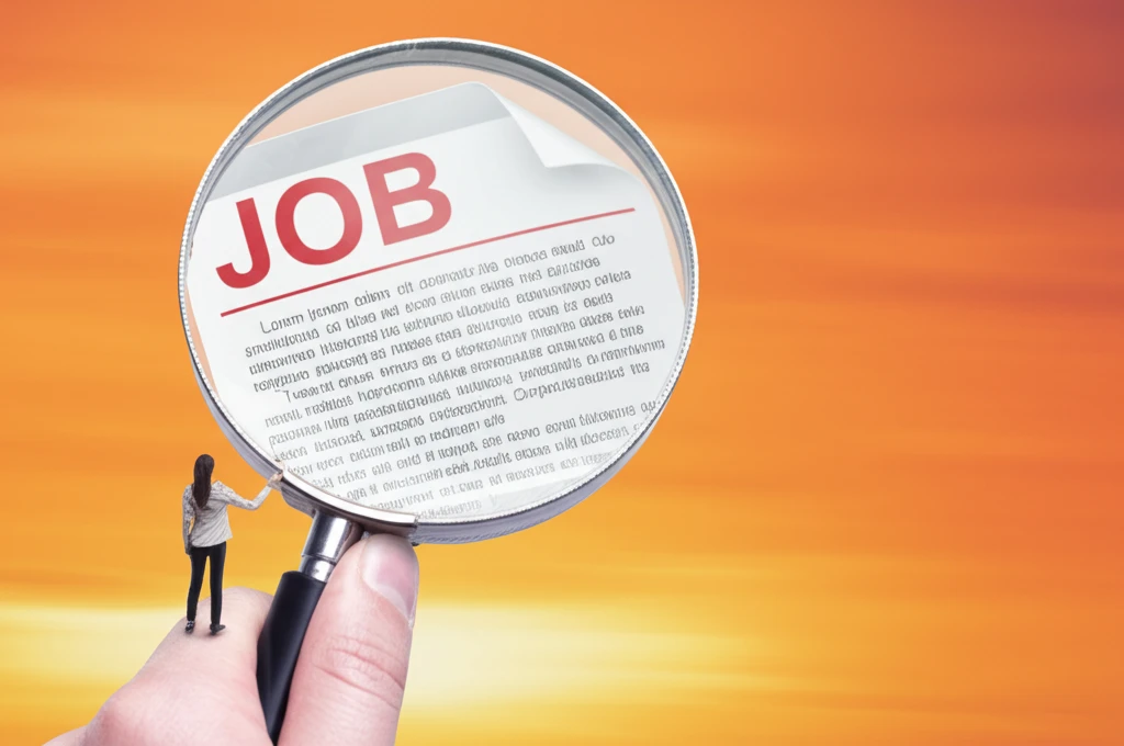 A person using a magnifying glass to decode hidden messages in a job ad.